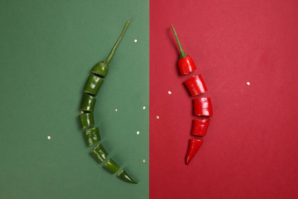 groene rode chili peper op groen rood papier achtergrond gesneden stukken zaden - Foto, afbeelding