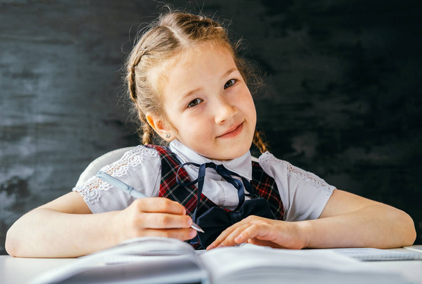 Portrait beautiful positive little schoolgirl sitting at her desk and doing her homework. Back to school concept. - Valokuva, kuva