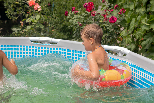 Το παιδί κολυμπάει και γελάει στην πισίνα. Καλοκαίρι ηλιόλουστη μέρα. Γαλάζιο και ζεστό νερό πισίνας - Φωτογραφία, εικόνα