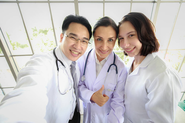 Група з трьох різноманітних людей, лікар і асистент, фотографують селфі разом із щасливими та усміхненими обличчями. Концепція успішної команди
. - Фото, зображення