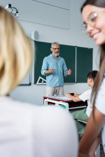 Зрелая учительница разговаривает со школьниками в классе  - Фото, изображение