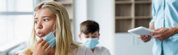 Estudante segurando máscara médica e respirando em sala de aula, banner  - Foto, Imagem