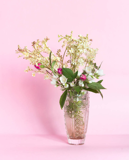 Bouquet of meadowsweet (Latin Filipndula), jasmine and wild roses in a vase on a pink background. - 写真・画像