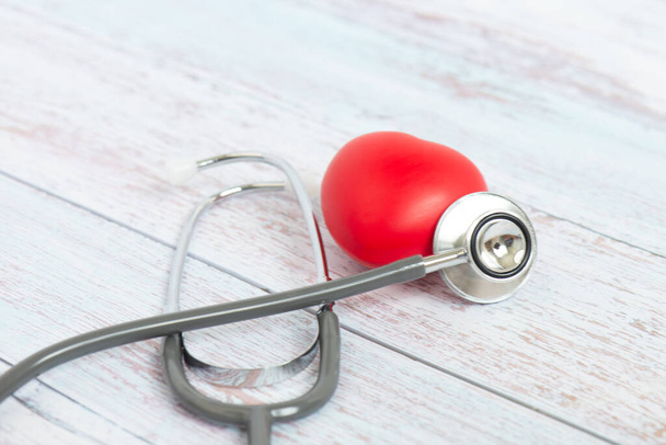 Červená koule tvar srdce a lékařské stetoskop na dřevěném stole. Zdravotní péče, Medicare a kardiologie koncepce. - Fotografie, Obrázek