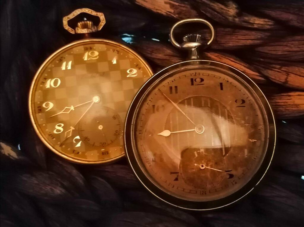 Po zbytek času tajný. Starožitné zlaté a stříbrné kapesní hodinky na tmavém přírodním pozadí vypadají opravdu tajemně a starobyle, jako by měřily čas věky.  - Fotografie, Obrázek