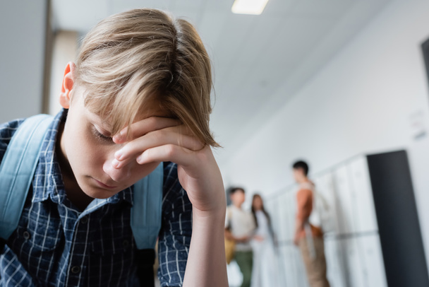 adolescente frustrado com a cabeça curvada perto de colegas de classe no fundo embaçado - Foto, Imagem
