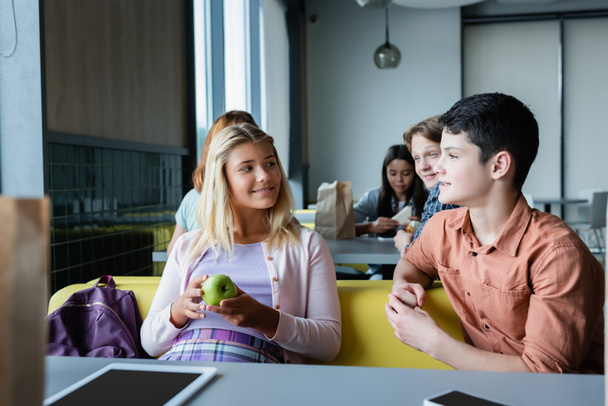 teenage friends talking during lunch break in school canteen - Фото, изображение