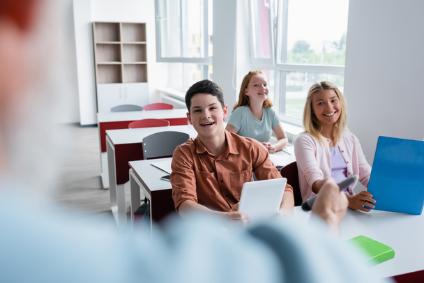 happy pupils looking at teacher on blurred foreground during lesson - Fotoğraf, Görsel