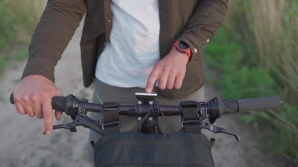 People, sports, active lifestyle concept. Cyclist using navigator device examines map and looks for GPS coordinates on screen of gadget while cycling outdoors. Activity tracker on handlebars of cycle - Footage, Video