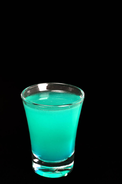 refrescante bebida alcohólica con bayas, vodka helado y ginebra, cáscara de limón servida en taza de vidrio en el mostrador sobre fondo borroso - Foto, imagen