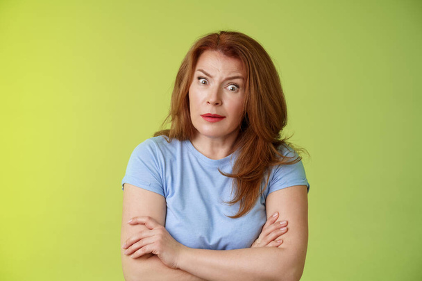 You did what. Confused shocked speechless redhead mature mother stare camera puzzled concerned cross arms chest self-soothing bothered pose look questioned hesitant green background - Photo, Image