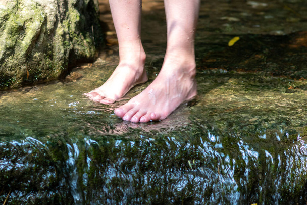 Молодий хлопчик грає босоніж з чистою водою на маленькій струмці, використовуючи ноги і воду весна охолоджує пальці ніг і ноги і освіжає чистим еліксиром життя в атмосфері медитації дзен
 - Фото, зображення