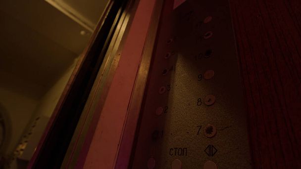 Κοντινό πλάνο θηλυκού χεριού πατάει τα κουμπιά του ασανσέρ. Στικ. Επιλογή των 8 και 9 ορόφων μέσα σε ένα παλιομοδίτικο ασανσέρ με πολύχρωμα φώτα που αναβοσβήνουν. - Φωτογραφία, εικόνα