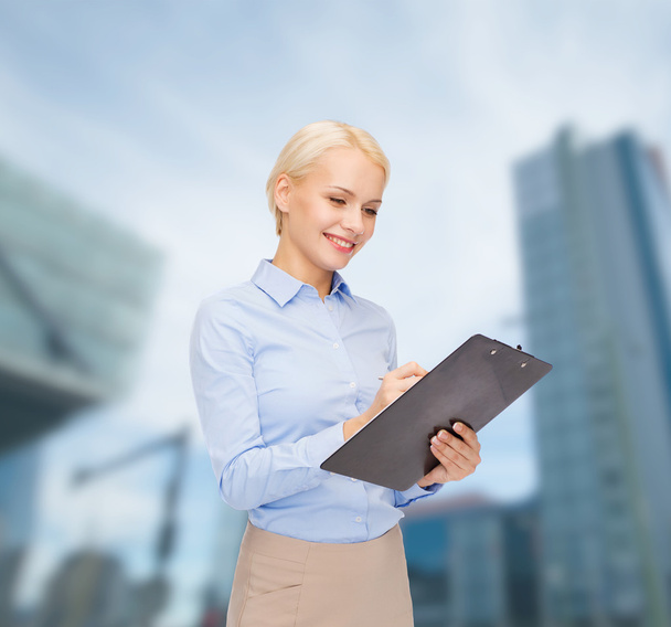 smiling businesswoman with clipboard and pen - Photo, image