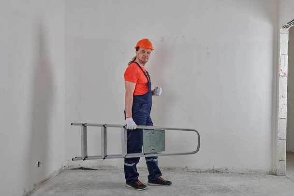 angry engineer holding a stepladder under his arm - Foto, Imagem
