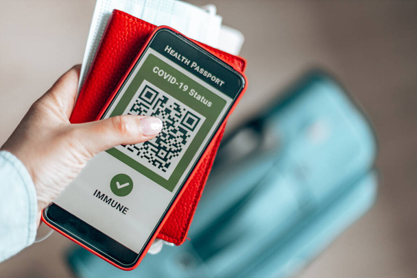 パスポート、チケットパス、スマートフォンを持っている女性旅行者は、流行期に旅行するためのデジタル健康パスポートアプリ. - 写真・画像