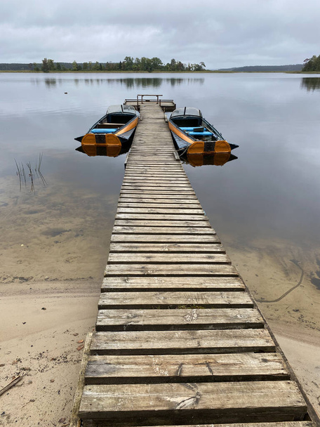 Rowing boat on the shores of Lake Seliger. Walkway on a sandy beach on a cloudy day  - Photo, image