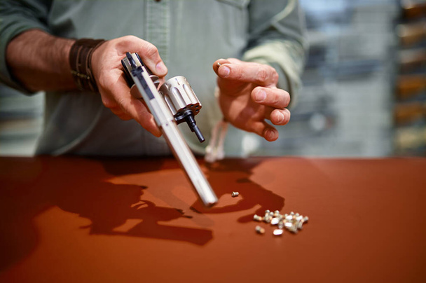 Man reload revolver at the counter in gun store - Foto, Imagem
