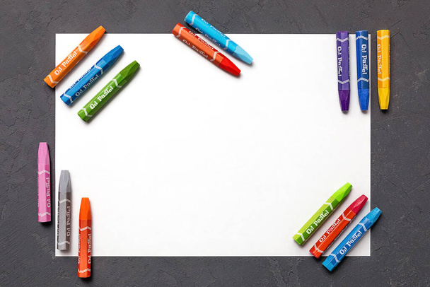 värilliset värikynät, joihin on kaiverrettu "öljypastelli", paperiarkki harmaalle pöydälle. Nuoren taiteilijan setti. luovuuden käsite. ylhäältä - Valokuva, kuva