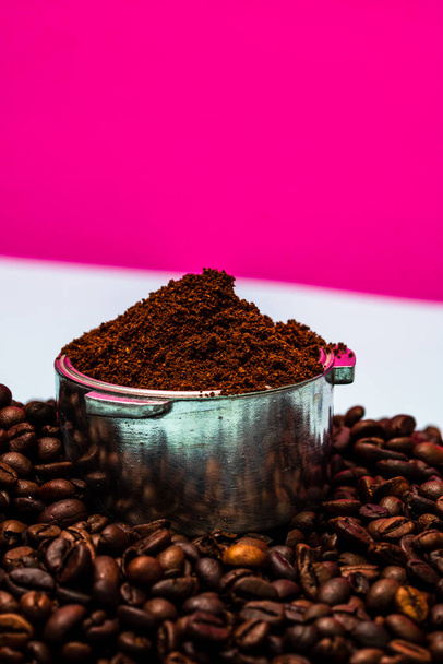 Grãos de café e portafilter com café moído em uma composição em um fundo rosa. - Foto, Imagem