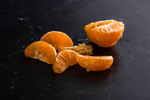 Snijd sinaasappels op zwarte achtergrond. Vers fruit geïsoleerd op zwart - Foto, afbeelding