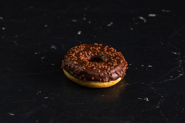 Chocolate glazed donut with chocolate chips isolated. Close up of delicious donut. - Fotó, kép