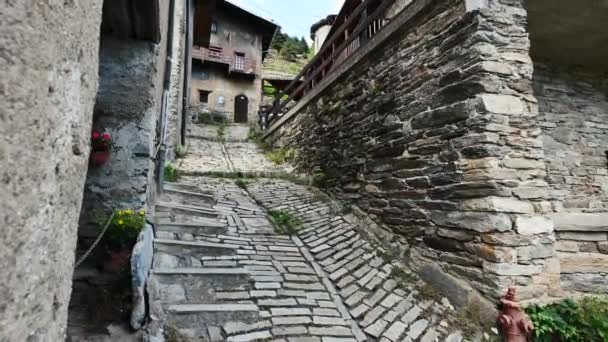 Észak-Olaszország, 2021. július. Egy elhagyatott ösvény egy hegyi faluban, a kőlépcső a falu házai között kanyarog. Gyönyörű nyári nap.. - Felvétel, videó