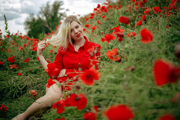kaunis tyttö pellolla punaisen unikon kanssa punaisessa paidassa - Valokuva, kuva