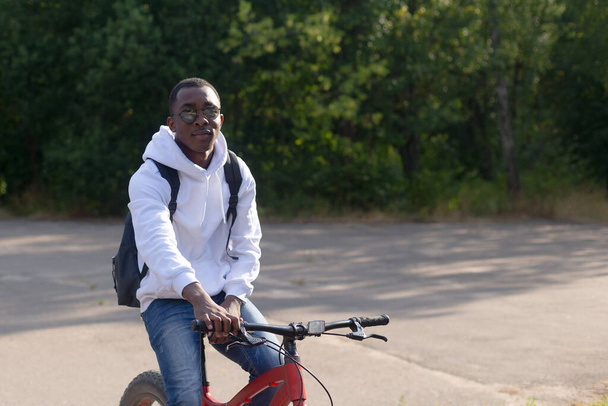 A young happy African-American man with a bicycle in nature. - Foto, Bild