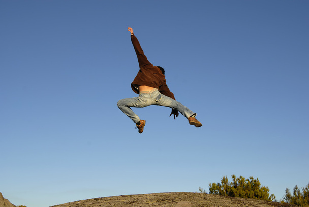 Молодий чоловік стрибає високо в горі
 - Фото, зображення