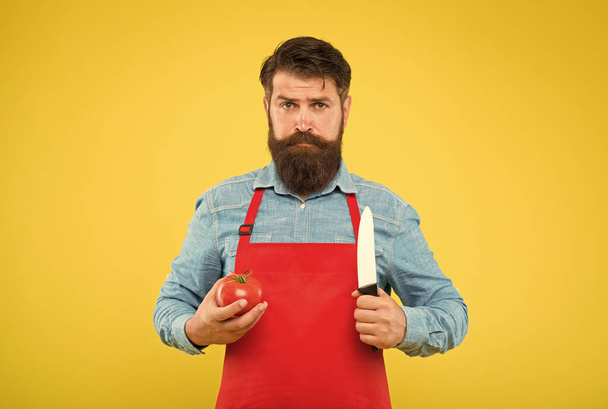 Serious hipster hold tomato and knife to cook fresh vegetable recipe for healthy diet, vegetarian - Zdjęcie, obraz