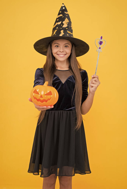 witchcraft and enchantment. childhood autumn holiday. teen girl ready to celebrate. costume party fun. happy halloween. child in witch hat. kid hold magic wand and spooky pumpkin. Ghosts Gather Here - Photo, Image