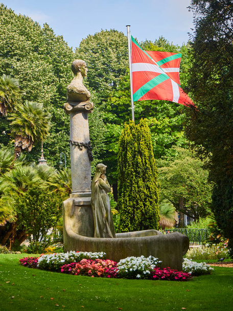 Pomnik Jose Maria Usandizaga na Plaza de Guipuzcoa Square wiyh flagi Kraju Basków w tle. San Sebastian, Gipuzkoa, Hiszpania. - Zdjęcie, obraz