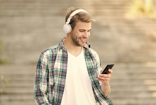 Disconnect from the outer world. Happy guy make video call using mobile phone. Handsome man listen to music on phone. Smart phone. Music player. MP3. Music app on phone. New technology. Modern life - Valokuva, kuva