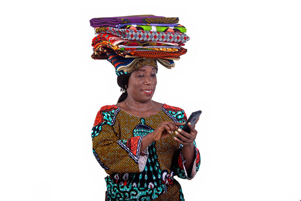 портрет красивої жінки з традиційними пов'язками на голові за допомогою мобільного телефону під час посмішки
. - Фото, зображення