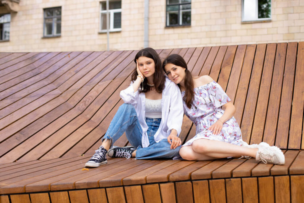 due ragazze sorelle sono sedute su una panchina di legno all'aperto - Foto, immagini