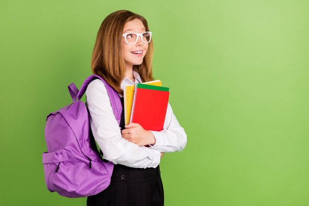Profile side view portrait of pretty cheerful dreamy intelligent girl holding materials copy space ad isolated over green color background - Φωτογραφία, εικόνα