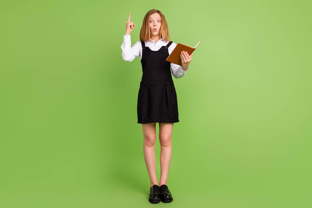 Full length body size view of pretty amazed girl reading vocabulary pointing up idea isolated over green color background - Photo, image