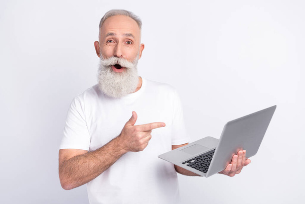 Portrait of attractive cheerful amazed man using demonstrating laptop screen isolated over light grey color background - Fotó, kép