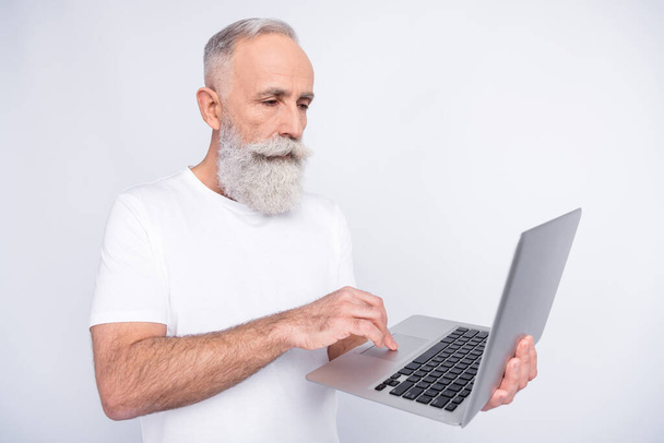 Photo of serious charming focused old man look hold laptop work freelance isolated on grey color background - Foto, imagen