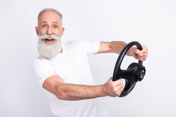 Photo of happy cheerful positive old man hold steering wheel smile rider isolated on grey color background - Foto, immagini