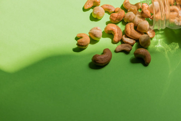 Scattered hazelnuts and cashews on a green background with a place to insert. - Fotó, kép