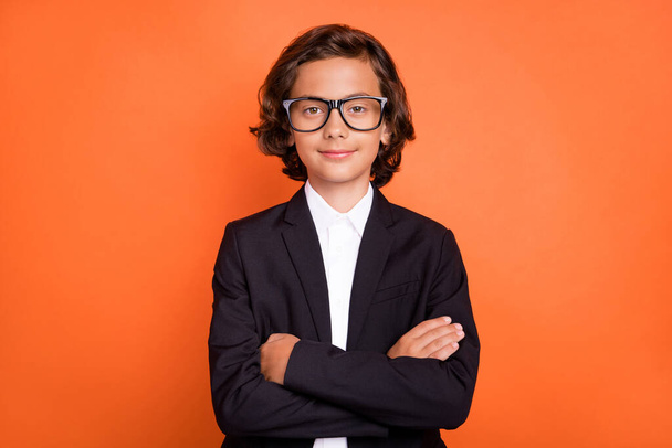 Photo of young confident charming happy boy hold hands crossed wear glasses isolated on orange color background - Photo, Image