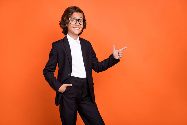 Photo of young happy positive small boy point finger empty space good mood news isolated on orange color background - Photo, image