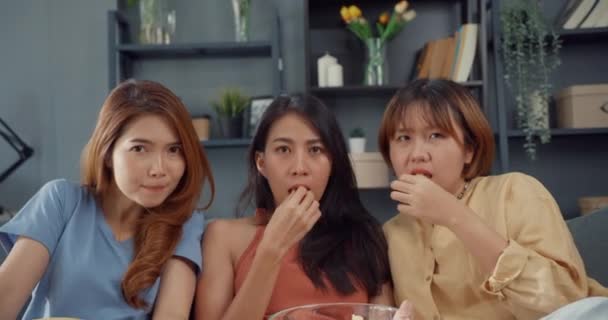 魅力的なアジアの素敵な女性の女の子のグループはショックを叫び、恐怖の瞬間は自宅のリビングルームでソファの上にポップコーンはホラーオンライン映画エンターテイメントを見て食べる。週末のライフスタイル活動隔離コンセプト. - 映像、動画