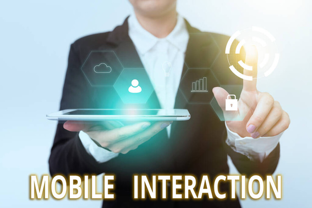 Podpis tekstowy przedstawiający Mobile Interaction. Biznes pomysł interakcji między użytkownikami telefonów komórkowych i komputerów Kobieta w garniturze Holding Tablet wskazując palec na futurystyczny wirtualny przycisk. - Zdjęcie, obraz