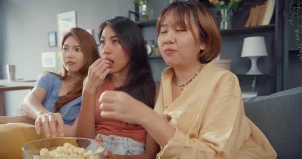 Приваблива азіатська жіноча група з приємністю радіє випадковим розвагам і насолоджується розвагами онлайн-фільмів на дивані у вітальні. Карантинна концепція життя. - Кадри, відео