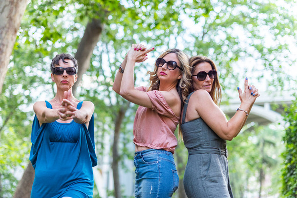 Three mature female friends making a gun gesture with their hands and posing. - Photo, Image
