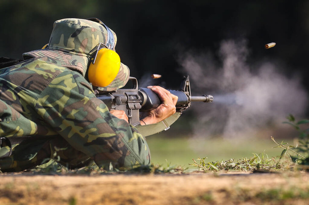 Soldier shooting rifle gun to target with bullet cartridge in the air - Foto, afbeelding