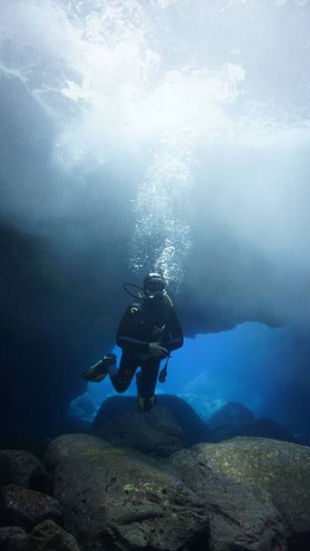 Υποβρύχια φωτογραφία ενός δύτη μέσα σε μια σπηλιά με μαγικό φως. Από μια κατάδυση στον Ατλαντικό ωκεανό. - Φωτογραφία, εικόνα